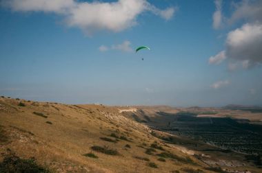 Parachutist gliding in blue sky over scenic landscape of Crimea, Ukraine, May 2013 clipart
