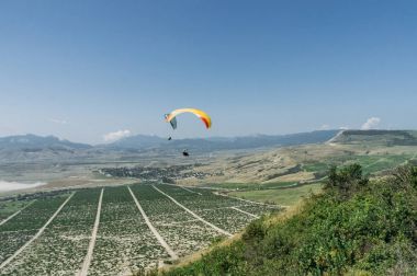 Parachutists gliding in blue sky over scenic landscape of Crimea, Ukraine, May 2013 clipart