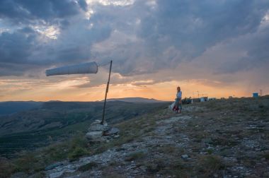 Woman walking in beautiful mountainous landscape with windsock waving in Crimea, Ukraine, May 2013 clipart