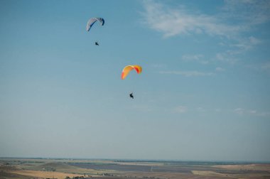 Parachutes in the sky over field in hillside area of Crimea, Ukraine, May 2013 clipart