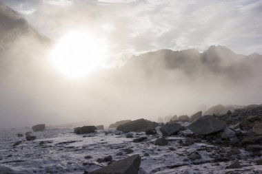 snow and rocks in mountains at misty morning, kyrgyzstan, ala archa  clipart