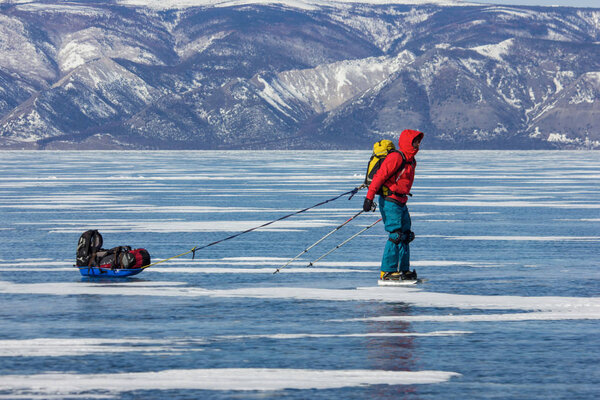 male hiker with backpack standing on ice water surface ,russia, lake baikal 