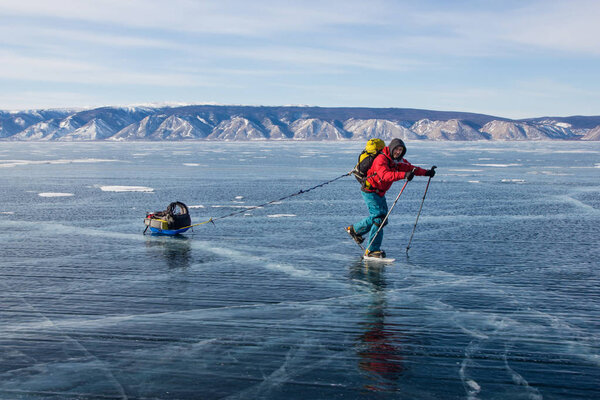 male hiker with backpack walking on ice water surface,,russia, lake baikal  