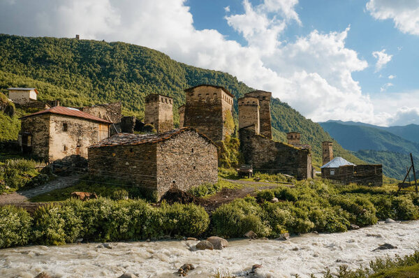 old weathered buildings against small river stream against hills, Ushguli, svaneti, georgia