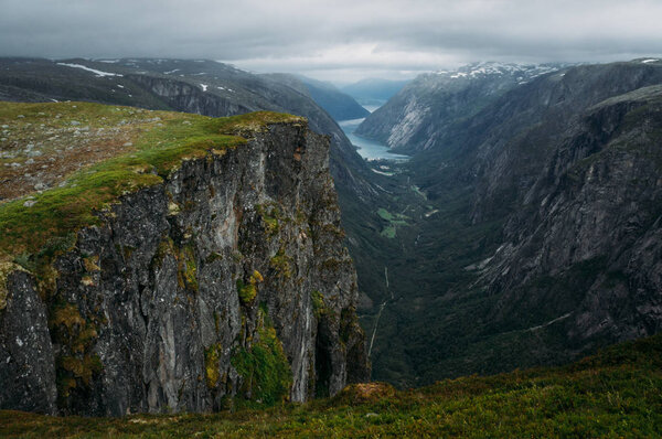 view of rocks and grassy cliff, mountain river on background, Norway, Hardangervidda National Park