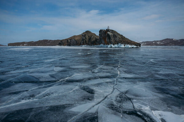 View of ice covered water surface of lake and rock formations on background, Russia, Lake Baikal