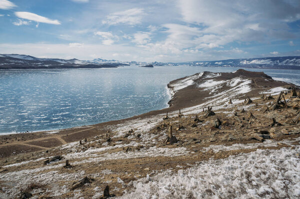 view of sandy mountain lake shore against water and hills on background, Russia, Lake Baikal
