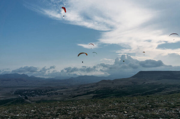 Parachutists gliding in blue sky over scenic landscape of Crimea, Ukraine, May 2013