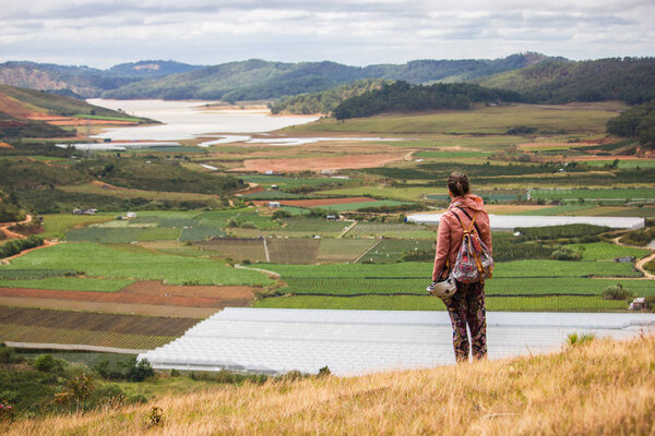 back view of man looking at beautiful landscape with agricultural fields and mountains, vietnam, dalat region