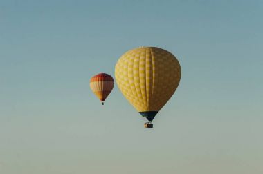 Hot air balloons flying in blue sky clipart