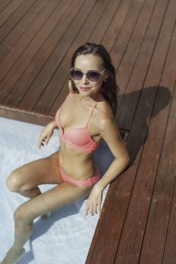pembe bikini havuzu kenarında oturan çekici genç kadın yüksek açılı görünüş