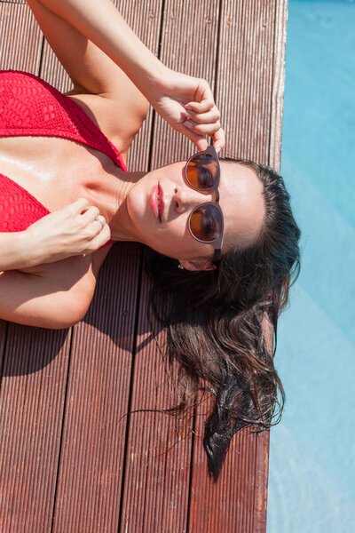 high angle view of young woman in bikini lying on poolside
