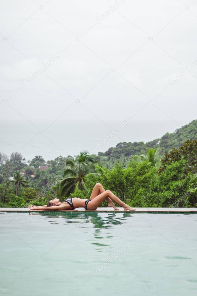 girl resting at swimming pool on tropical resort