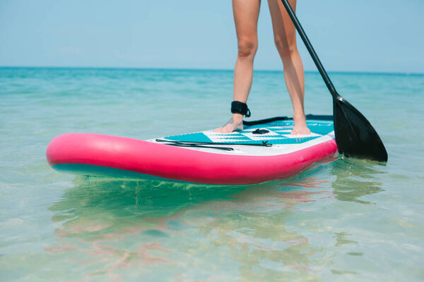 cropped view of woman on stand up paddle board on sea 