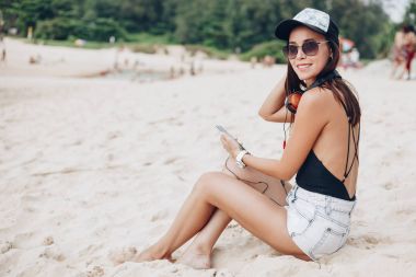 çekici kadın plajda kulaklık ile müzik dinleme Smartphone kullanarak