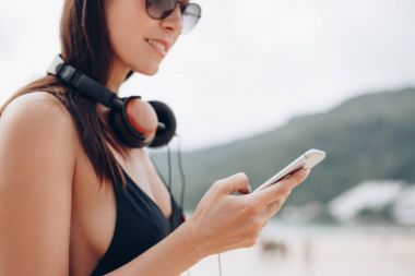 çekici kadın güneş gözlüğü ve smartphone kullanarak kulaklık ile kap