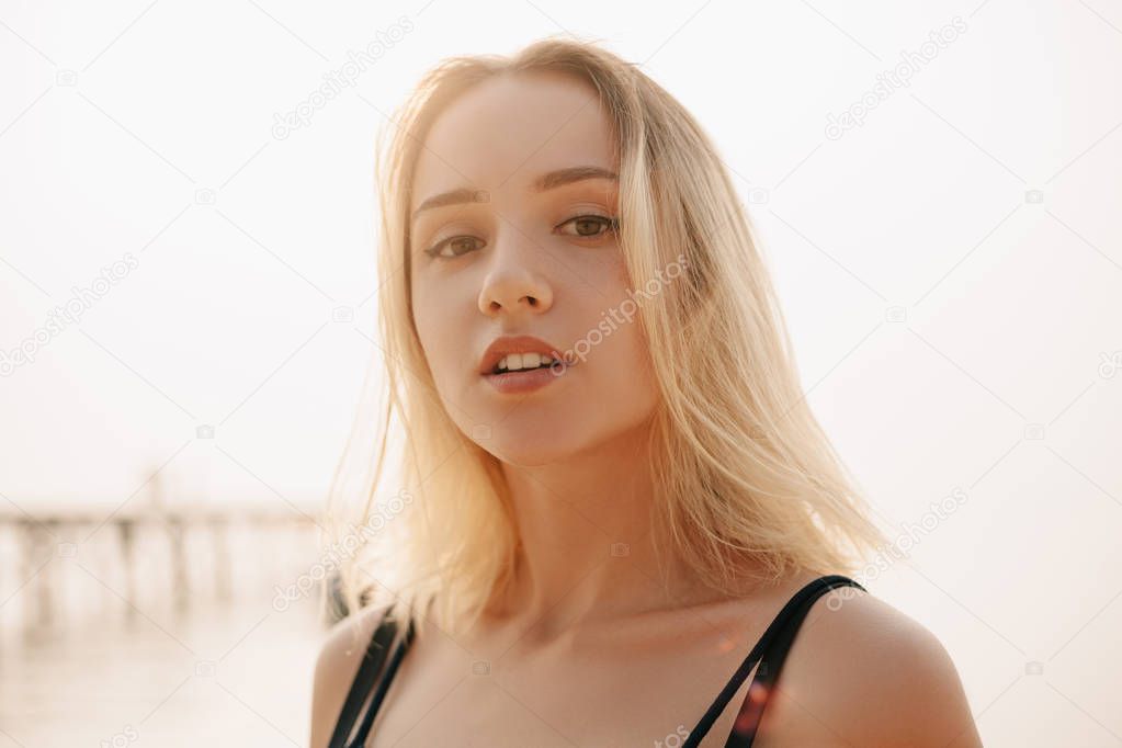 portrait of beautiful girl in dress looking at camera on beach