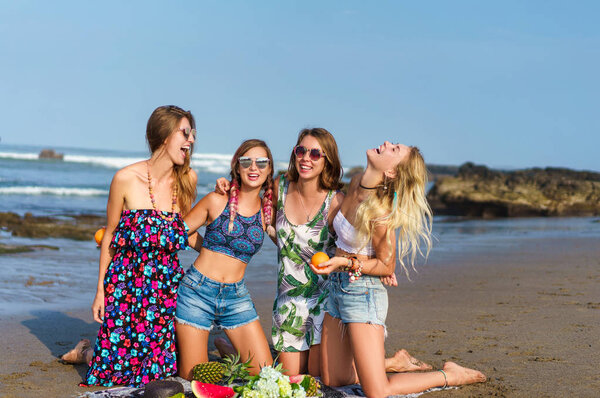 group of beautiful young women with various fruits spending time on beach