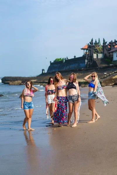 group of stylish young women in bikini posing on beach