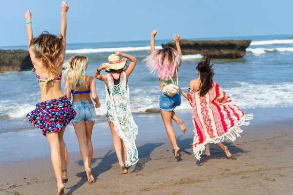 rear view of group of young women running at sea