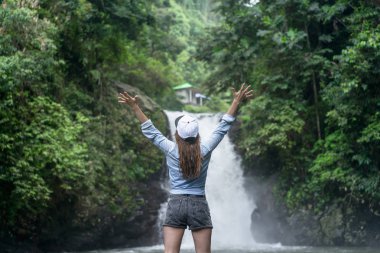 arkadan görünüşü kadın uzanmış silah Aling-Aling şelale ile arka planda, Bali, Endonezya