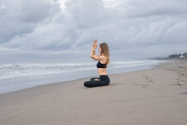 pratik Yoga bulutlu gün sahil üzerinde lotus poz güzel genç kadın