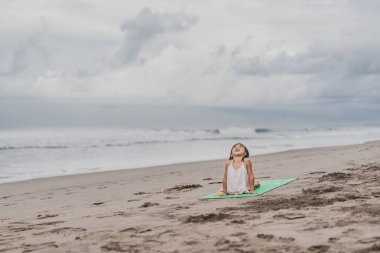 mutlu küçük çocuk pratik yoga Upward bakan köpek (Urdhva Mukha Svanasana) poz sahil üzerinde