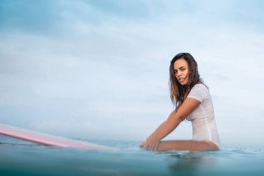 sörf tahtası Okyanusu üzerinde ıslak beyaz mayo güzel genç kadın yan görünüm