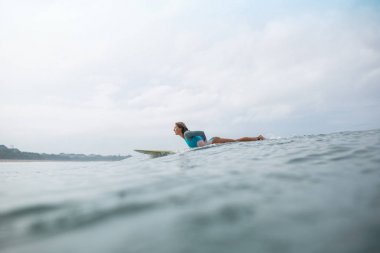 sörf tahtası okyanusta sürme sportif genç kadın yan görünüm