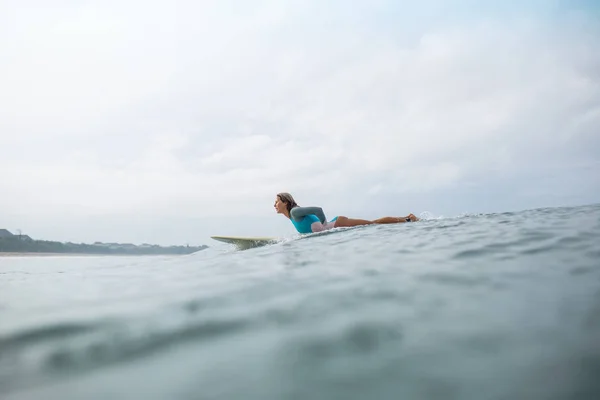 海でサーフボードに乗って陽気な若い女性の側面図 — ストック写真