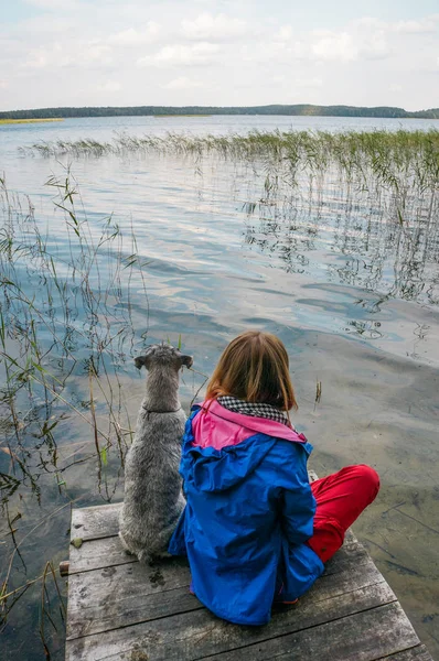 Chica y perro en el lago — Stock Photo