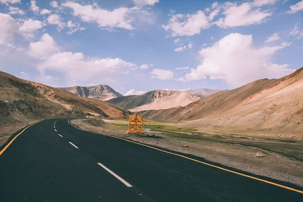 Асфальтовая дорога с дорожным знаком в индийских Гималаях, Ладакхская область — стоковое фото
