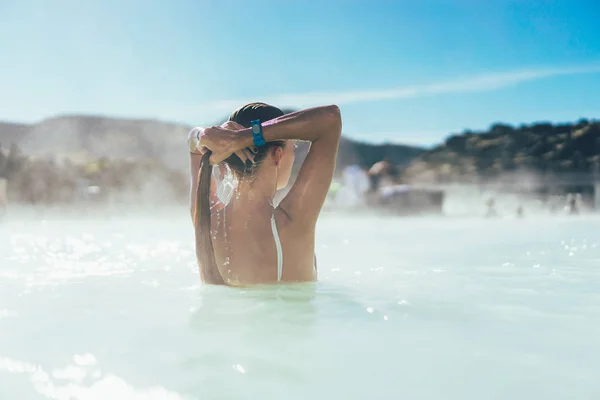 Vue arrière de la jeune femme se détendre dans la piscine chaude en Islande — Photo de stock