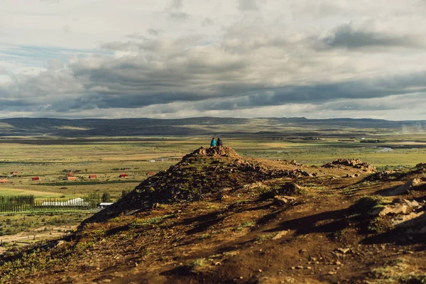 Vue arrière du couple assis sur une falaise et regardant le paysage sauvage pittoresque en Islande — Photo de stock