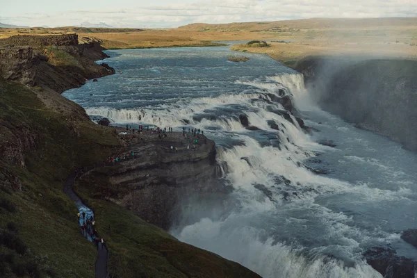 Gruppo di turisti che guardano maestosa cascata in Islanda — Foto stock