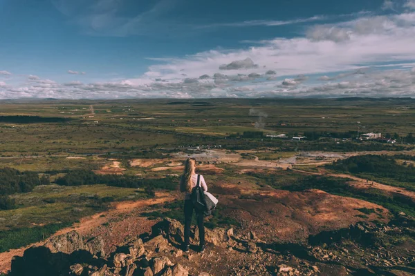 Vista para trás da jovem mulher de pé no penhasco e olhando para a paisagem majestosa na Islândia — Fotografia de Stock