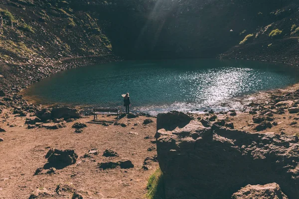 Vista posterior de la joven mujer mirando el hermoso lago del cráter escénico en Islandia - foto de stock