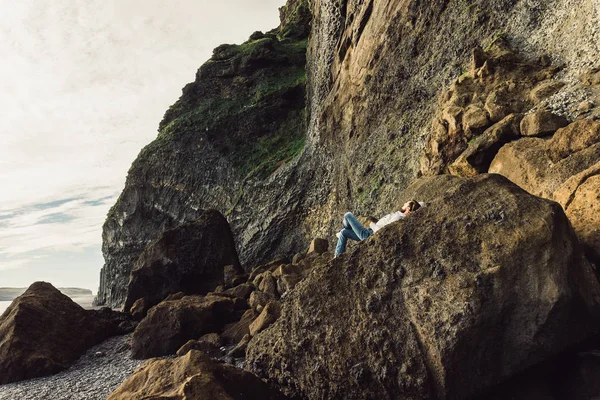 Молодой человек лежит на скале и наслаждается величественным ландшафтом — стоковое фото
