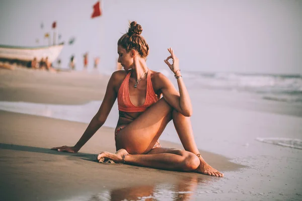 Jovem mulher em maiô praticando ioga na praia em goa — Fotografia de Stock