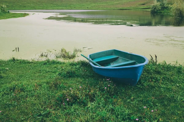 Синій човен на зеленій траві поблизу прекрасними річковими Алтай, Росія — стокове фото