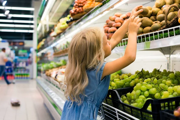 Adorable female child choosing fruits in supermarket — Stock Photo
