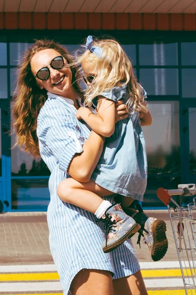 Feliz madre con estilo y adorable hija en gafas de sol - foto de stock
