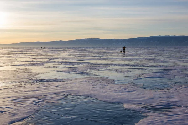 Caminhante masculino com mochila andando na superfície da água gelada contra colinas na costa, Rússia, lago baikal — Fotografia de Stock