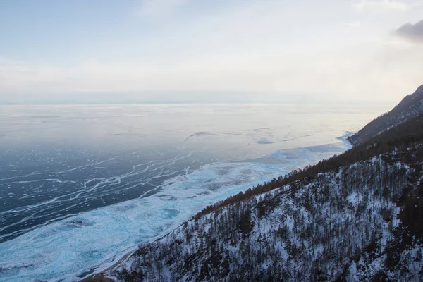 Berghang mit Bäumen gegen Eiswasseroberfläche, Russland, Baikalsee — Stockfoto