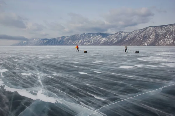 Чоловічі мандрівники з рюкзаками, що ходять по поверхні крижаної води вдень, Росія, озеро Байкал — стокове фото