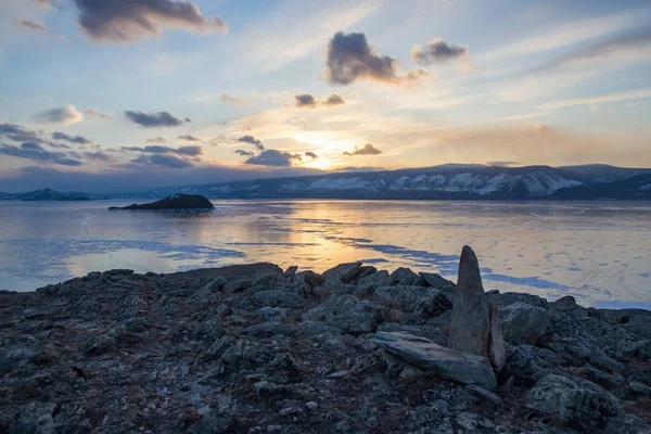 Перегляд озеро з льодом поверхні і скелі утворень на березі на захід сонця, Росія, озеро Байкал — стокове фото