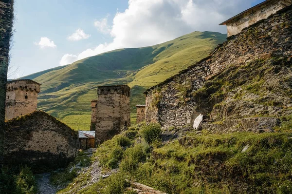 Vue du champ herbeux avec de vieux bâtiments ruraux altérés et des collines sur le fond, Ushguli, svaneti, géorgie — Photo de stock