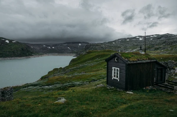 Casa rural sobre campo com grama verde contra pequena lagoa, Noruega, Hardangervidda National Park — Fotografia de Stock