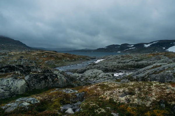 Vue sur un terrain rocheux avec lac en arrière-plan entouré de collines, Norvège, Parc national Hardangervidda — Photo de stock