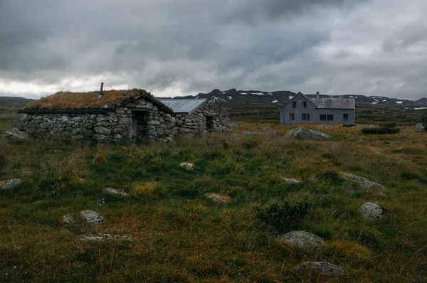 Vecchie case climatizzate sul campo con erba alta e pietre, Norvegia, Hardangervidda National Park — Foto stock